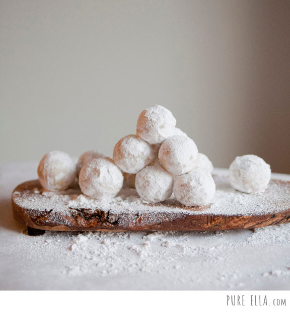 Image shows a stack of snowball cookies on a wood tray